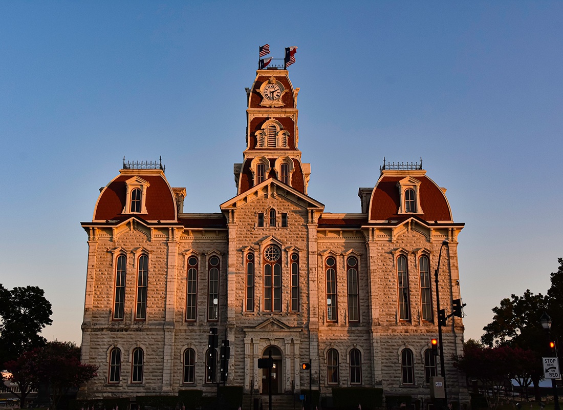 About Our Agency - View of the Historic Courthouse Building in Weatherford Texas Next to Trees in the Evening with a Clear Sky